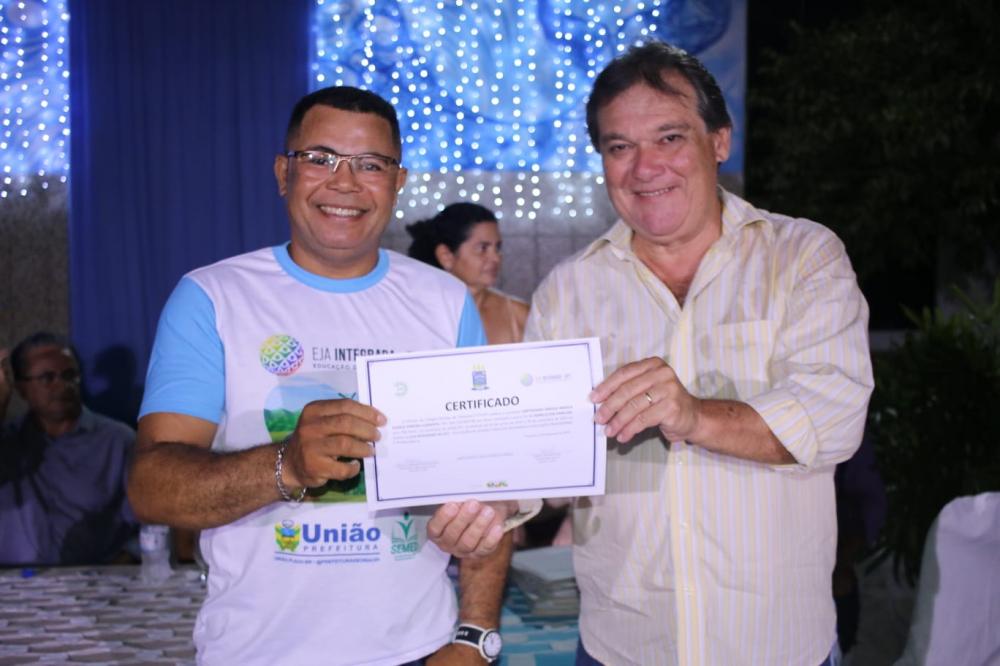 prefeito Gustavo Medeiros fazendo a entrega para aluno 